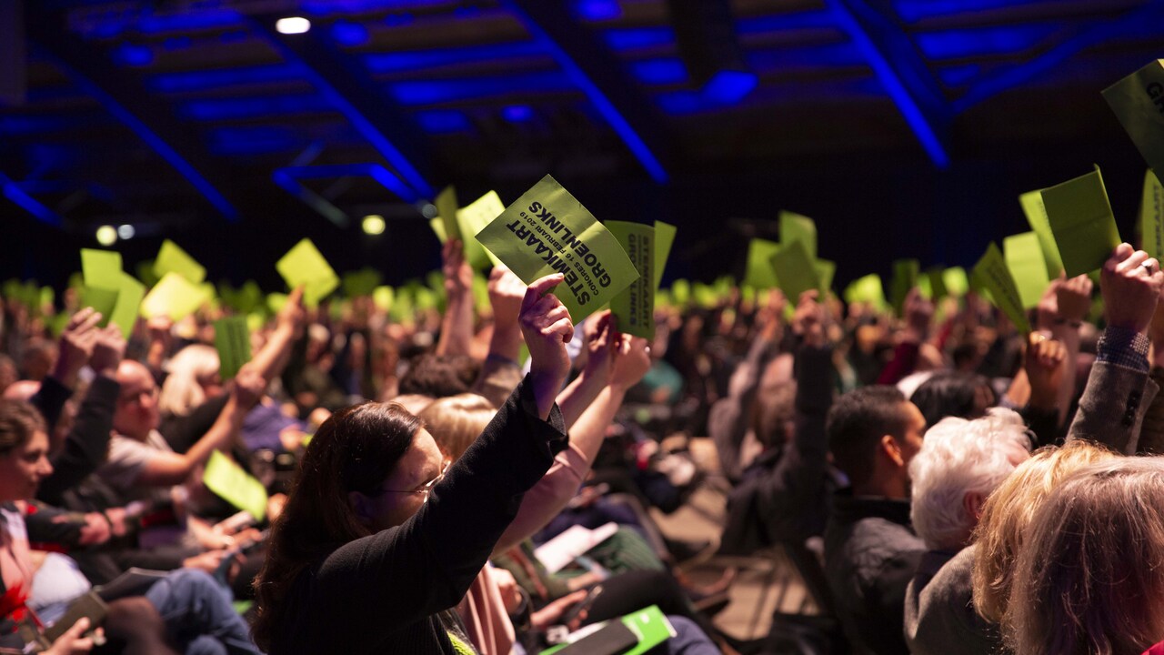 Leden houden op het congres de groene stemkaart omhoog om hun stem uit te brengen op een ingediende motie.